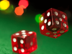  Closeup of two red dice landing on green felted craps table.